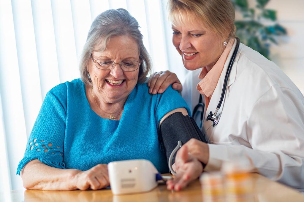Senior Adult Woman Learning From Female Doctor to Use Blood Pressure Machine.